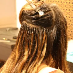 This image shows the application of micro-ring hair extensions. These tiny beads provide a secure, long-lasting way to add length and volume without damaging your natural hair.