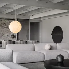 The formal living room of the Vaulted Haus showcases a refined grey scale material palette. The texture of the bouclé sofa, the smooth black coffee table, and the vaulted ceiling create a rich, monochromatic scheme.