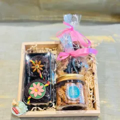 This Rakhi gift hamper includes Rakhi-themed chocolate cupcakes, a jar of our signature cookies, and other assorted goodies, all packed in a rustic wooden tray.