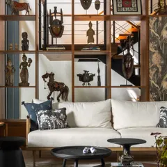 This custom open shelving unit acts as a permeable screen, displaying the client's collection of artifacts and sculptures while defining the living area. It turns the home into a gallery of personal memories.