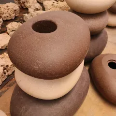 A stack of our unique pebble-shaped FRP planters. Available in earthy tones like brown and beige, these are designed for modern gardens and patios.