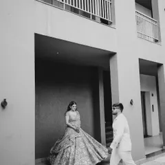 A creative black and white portrait. The composition, with the groom walking towards his bride, creates a sense of anticipation and story.