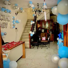 Here is a complete room setup to welcome a baby boy. The decor includes blue and silver "Welcome Baby" balloons, flower-shaped balloon clusters on the walls, and a beautiful arrangement of rose petals on the table.