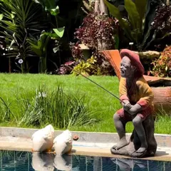 I often use whimsical sculptures to add personality to a garden. This charming statue of a fisherman by the poolside adds a playful and serene touch to the space.