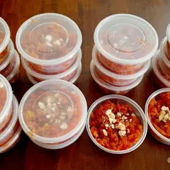 A bulk order of my homemade carrot halwa, packed and ready for an event. Each container is topped with chopped nuts for extra flavor and texture.
