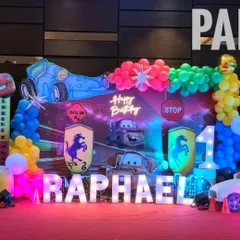 A high-energy Disney Cars theme for Raphael's first birthday. The setup includes character cutouts of Lightning McQueen and Mater, a racetrack-inspired backdrop, and marquee letters spelling out the name.