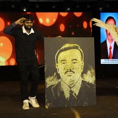 The final reveal of a glitter portrait on a grand stage. The combination of lighting, performance, and the sparkling art creates a memorable spectacle for any large-scale event.