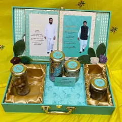 A luxurious hamper box designed for a special event, featuring custom invitations and jars of goodies, all presented in a beautiful sea-green case.