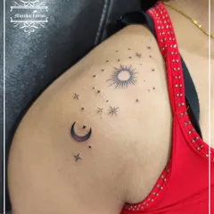A beautiful celestial tattoo on the shoulder, featuring the sun, moon, and a sky full of stars.