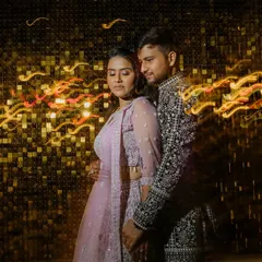 An abstract couple portrait using slow shutter speed to create dynamic light trails against a glittering gold background. This technique adds energy and a celebratory feel to sangeet photos.