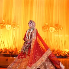 A stunning full-length shot of the bride, her red and gold lehenga catching the light beautifully. Her twirl shows off the magnificent flare of her dress, making her look like a queen.