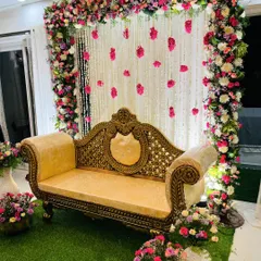 A beautiful floral frame for an engagement or reception. The stage is decorated with a dense arrangement of pink and white flowers, with hanging garlands creating a romantic backdrop.