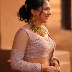 A candid, close-up shot of the bride's happy expression. This photo highlights her intricate gold necklace and the delicate sequin work on her blouse.