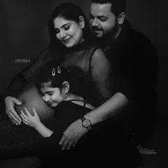 A family eagerly awaiting their new arrival. This black and white family maternity portrait captures the love and connection as a big sister listens for the baby's kicks.