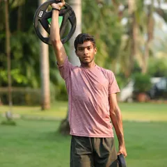 Strength training in the serene landscapes of our Goa camp. This athlete is performing an overhead plate hold, a great exercise for building shoulder stability and core strength.