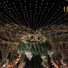As day turns to night, the magic truly comes alive. This grand floral mandap, transformed under a canopy of thousands of twinkling fairy lights, creates an enchanting and romantic atmosphere for an evening wedding ceremony.