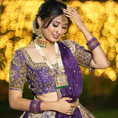A beautiful shot showcasing the intricate handwork on this purple and silver semi-bridal lehenga. The blouse features detailed embroidery, and the entire outfit is designed to make you shine, especially with the beautiful bokeh lights in the background.