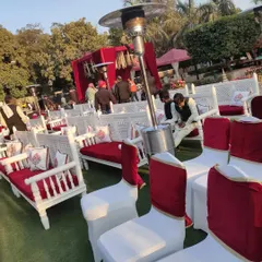 This setup combines traditional white carved benches with red cushions and standard banquet chairs. The inclusion of outdoor heaters ensures guest comfort during colder evening functions.