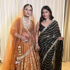 Standing with the beautiful bride. I'm wearing a black saree with striking silver and gold stripes, a modern take on traditional Indian wedding attire that is both elegant and eye-catching.