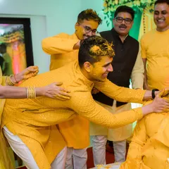 More friends join in on the fun, ensuring the groom is thoroughly covered in turmeric. These are the moments of pure, unscripted fun.