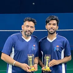 Two of our senior players and coaches proudly holding their trophies after a successful tournament, showcasing their team's matching jerseys.