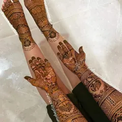 This image shows a full bridal mehndi application, with intricate designs covering the arms and legs, creating a stunning and complete look for the bride.