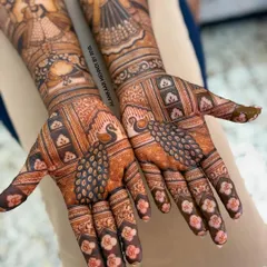A closer look at the palms of this bridal design, showcasing the symmetrical peacock figures and detailed floral work on the fingers.