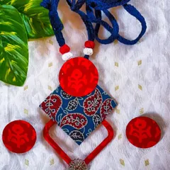 I love mixing prints, and this piece combines a classic blue paisley Kalamkari fabric with a bold, hand-painted red circular element. The geometric structure and contrasting colors create a striking, modern ethnic look. The set includes matching circular stud earrings.
