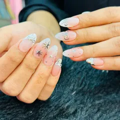 A dreamy, celestial-themed manicure. This set features a soft, milky white ombre base adorned with delicate silver stars and tiny bow charms for a touch of sparkle and magic.
