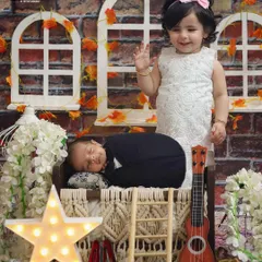 A magical moment between a big sister and her new baby brother. This creative studio setup with stars and soft lighting makes their first portrait together extra special.