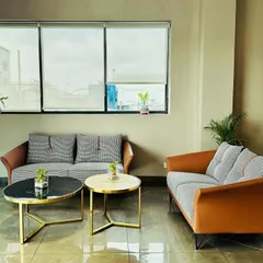 The waiting area at the M/s ALP project features a mix of two-seater and three-seater sofas in contrasting grey and tan upholstery. The nested coffee tables with marble and metallic finishes add a touch of modern luxury.