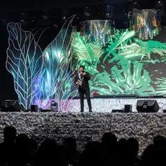 A solo performance on the grand Sangeet stage. The backdrop features a mix of abstract light structures and a vibrant tropical graphic on the LED screen, showcasing the versatility of our stage designs.