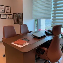 A view of the client-facing side of an executive desk. The setup is clean and professional, with comfortable visitor chairs and ample table space for meetings.