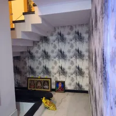 A subtle tree pattern wallpaper adds texture and interest to the often-overlooked space under a staircase. This monochrome design creates a sense of depth and brings a calming, natural element to the home's interior.