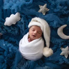 A peaceful newborn dreaming amongst the stars. My celestial-themed sessions use soft fabrics and props to create a magical, sleepy setting for your little one's first portraits.