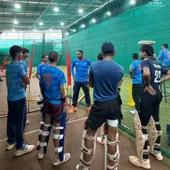 A team briefing in the nets. The coach discusses tactics and gives instructions to a group of attentive players before a drill.