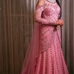 For the modern bride who dreams of a fairytale moment. This fully hand beaded pink gown features a flattering silhouette, cold shoulder details with delicate tassels, and a flowing train, designed for an unforgettable reception or gala.