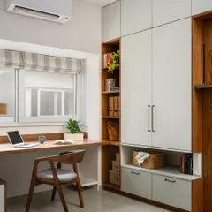A view of the 'Palaash' home office with the Murphy bed folded away. The design seamlessly integrates a full-sized wardrobe, open shelving, and a spacious work desk that runs along the window.