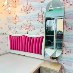 A whimsical bedroom designed for a princess, featuring a vibrant pink velvet headboard and a custom-themed wallpaper. The attached dressing table with an oval mirror completes this fairy-tale look.