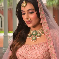 The soft veil adds a layer of ethereal grace to this pink bridal look. The makeup is kept soft and rosy, with beautifully defined eyes and glowing skin that looks perfect for a modern bride.