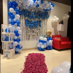 A complete "Welcome Home Boy" setup featuring a balloon arch, a silver shimmer curtain, and a rose petal pathway for a grand entrance.