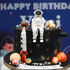 An out-of-this-world cake for a space-themed birthday party. This detailed creation features an astronaut, a rocket ship, and planets, making it a perfect centerpiece for a future explorer's celebration.