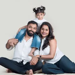 A classic family-of-three portrait. The daughter perched on her father's shoulders adds a playful touch to this happy and relaxed studio photo.