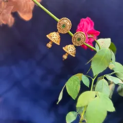 Elegant gold-plated jhumkas with green stone studs. A versatile piece that can be paired with many different traditional outfits.