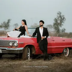 A stylish couple poses with a classic red convertible for their vintage-themed pre-wedding shoot in a rustic Goan landscape. This showcases how we can incorporate unique props to tell your story.