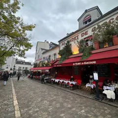 A classic café scene on a cobblestone street in Montmartre, Paris. The way these historic buildings seamlessly integrate with daily life, with their bright red awnings and bustling terraces, is a constant source of inspiration for adaptive reuse.