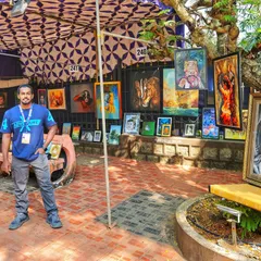A proud moment, standing at my stall during the KALAPARBA art event. My paintings are displayed for everyone to see, featuring a mix of animal portraits, spiritual art, and cultural pieces.