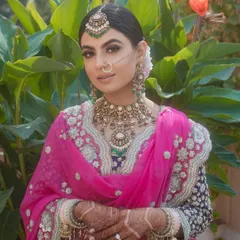A radiant Sikh bride in an outdoor setting. The neat bridal bun I styled for her keeps the focus on her beautiful features and stunning bridal attire, while ensuring her headwear remains perfectly in place.