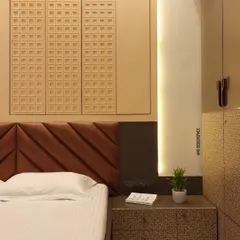 This master bedroom in Santacruz features a custom upholstered headboard with a diagonal pattern and textured wall panels above it. The bedside table and wardrobe have a unique patterned finish, adding a layer of detail to the room.