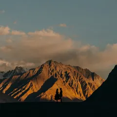 A powerful silhouette against the golden hour glow on the mountains of Leh. This shot highlights the epic scale of nature and the intimate connection of the couple.